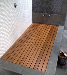 a wooden floor in a bathroom next to a bucket and spoons on the ground