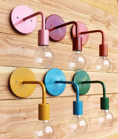 several colorful lights mounted to the side of a wooden wall next to a light bulb