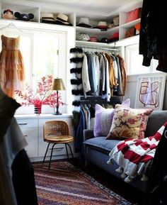 a living room filled with furniture and lots of clothes hanging on the wall next to a window