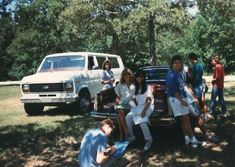 some people are sitting on the back of a car and one is taking a photo