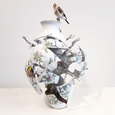 a bird is perched on the top of a vase that has been decorated with birds