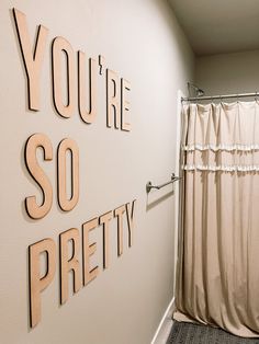 a bathroom with a shower curtain and some words on the wall above it that says you're so pretty