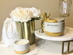 a marble table topped with two vases and white flowers next to eachother