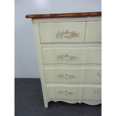 a white dresser with ornate carvings on the drawers