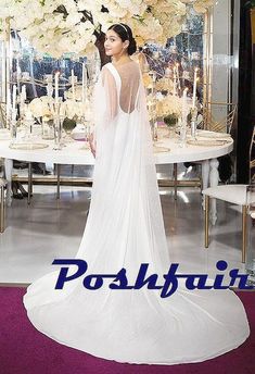 a black and white photo of a woman wearing a wedding dress in front of a table with flowers