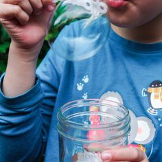 a young boy holding a glass jar filled with liquid