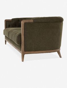 a green couch sitting on top of a white floor next to a wooden frame chair