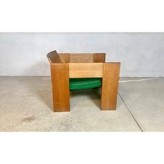 a small wooden table with a green cushion on it's seat and back rest