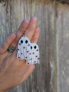 a hand holding a beaded dog keychain on top of a wooden fence