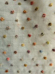 an up close view of some small beads on a white fabric material with many colors