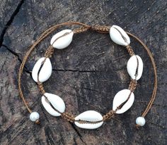 a bracelet made out of shells on a piece of driftwood with rope and beads