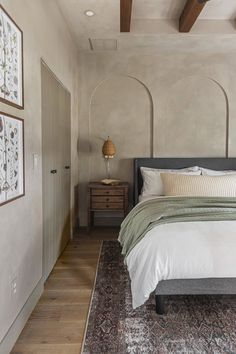 a bedroom with a bed, rug and two framed pictures on the wall above it