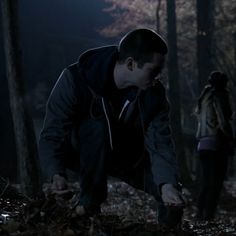 two people in the woods at night, one is bending down to pick up something