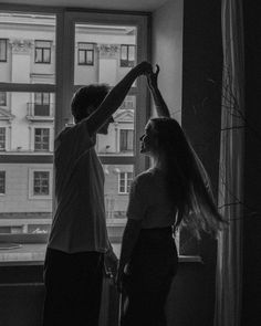 black and white photograph of two people standing in front of a window with long hair