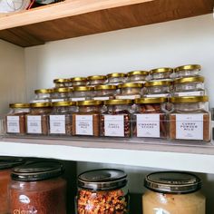 many jars are stacked on the shelf with food in them and there is also a clock