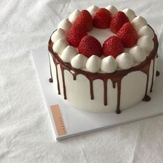 a white cake with chocolate and strawberries on top is sitting on a paper towel