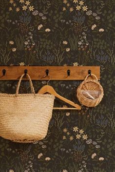 a wooden coat rack with two baskets hanging from it's hooks and a wallpapered background