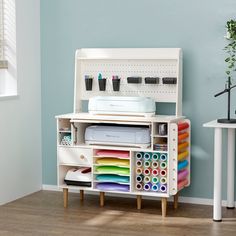 a sewing machine sitting on top of a white cabinet filled with craft supplies and paper