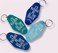 four different colored keychains with words on them, one is blue and the other is green