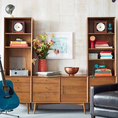 a living room filled with furniture and a guitar on top of a wooden cabinet next to a chair