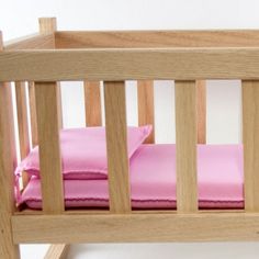 a wooden crib with pink sheets and pillows