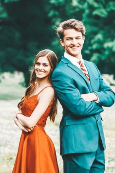 a man in a suit and tie standing next to a woman wearing an orange dress