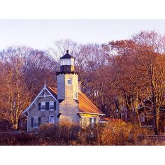 an old brick lighthouse surrounded by trees in the fall