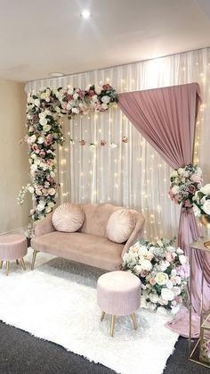 a living room decorated in pink and white with flowers on the wall, couches, tables and chairs