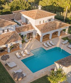 an aerial view of a house with a swimming pool and lounge chairs in the foreground