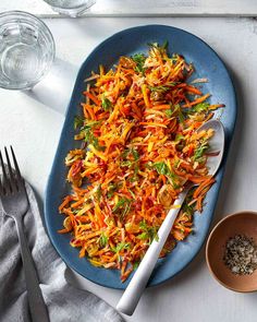 a blue plate topped with shredded carrots next to two small bowls