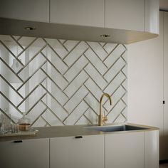 a kitchen with white cabinets and a gold faucet