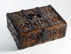 an old wooden box with carvings on the inside and sides, sitting on a white surface