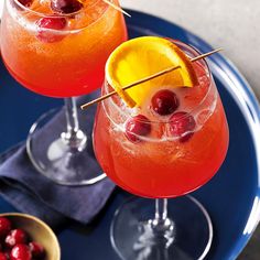 two glasses filled with drinks sitting on top of a blue plate