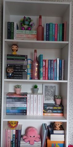 a bookshelf filled with lots of books next to a stuffed animal and other items