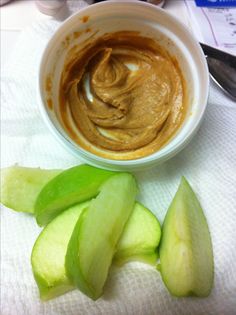 a bowl filled with peanut butter next to sliced up cucumbers on a table