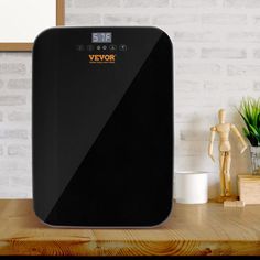 an image of a large black device on a wooden table in front of a brick wall