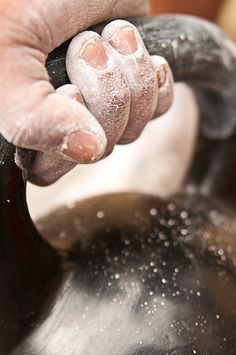 a person's hand holding onto the handle of a black kettle with white powder on it