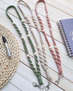 three lanyards and a notebook on a wooden table next to a straw hat