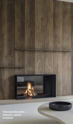 a modern fireplace in the middle of a room with wood paneling on the walls