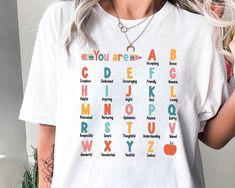 Teacher Shirt, ABC Affirmation Shirt, Alphabet Shirt, Back To School, Custom Teacher Shirt, Kindergarten Teacher, Teacher Appreciation Gift ↓ Click here to view our additional fashionable collections ↓ https://handcraftedbyhelenn.etsy.com Product Details: - 100% Cotton (fiber content may vary for different colors) - Medium fabric (5.3 oz/yd2 (180 g/m2)) - Classic fit - Tear away label - Runs true to size Care instructions: - Machine wash: warm (max 40C or 105F); - Non-chlorine: bleach as needed; Long Sleeve White T-shirt For Teacher Appreciation, White Crew Neck Shirt For Teacher Appreciation, White Text Print Shirt For Teacher Appreciation, Alphabet Shirt, Kindergarten Teacher, Teacher Teacher, Teacher Appreciation Gift, Kindergarten Teachers, Teacher Appreciation Gifts