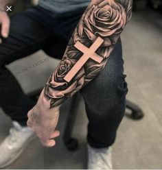 a man with a cross and roses tattoo on his arm