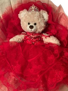 a teddy bear in a red dress with a tiara on it's head