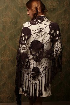 a woman wearing a white jacket with crocheted skulls on it