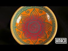 an orange and green bowl with designs on the bottom is sitting on a black surface