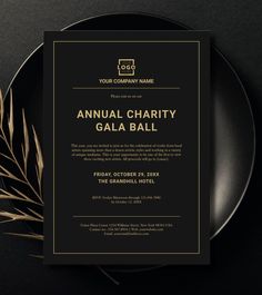 a black and gold wedding card on top of a plate next to a leafy twig