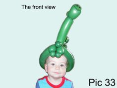 a little boy wearing a green hat and holding an inflatable balloon over his head