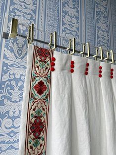 the curtains are hanging in front of an ornate wallpaper with red beads on them