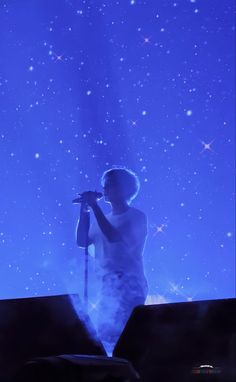 a man standing in front of a stage holding a microphone and singing into the air