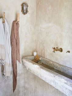 a bath tub sitting next to a wall with towels hanging on it's hooks