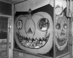 an old photo of two pumpkins on display in a store window with faces painted on them